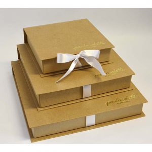 23 caixa tipo book, revestimento em papel kraft, personalização em couro sitético dourado.